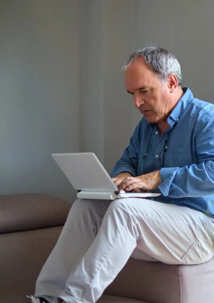 senior-business-owner-sitting-on-a-couch-using-a-laptop-to-plan-his-company-succession-strategy-and-retirement-wealth-management-portfolio