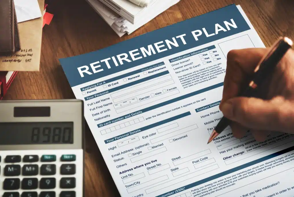 hand-with-pen-filling-out-a-retirement-plan-application-form-on-a-desk-next-to-a-calculator-for-fiduciary-wealth-management